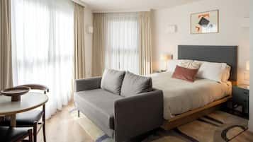 A hotel room with a bed, a sofa, a small table, and a chair.
