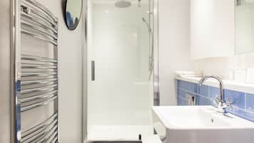 A modern bathroom with a glass-enclosed shower, a white sink, and a towel rack.