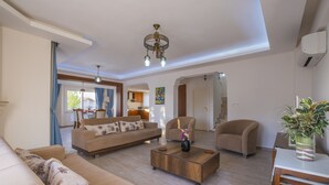 A spacious living room with a sofa set, a coffee table, and a chandelier. - Infinity Civan Villa (Fethiye)