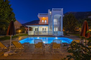 Un edificio de dos pisos con piscina y sillas de descanso.