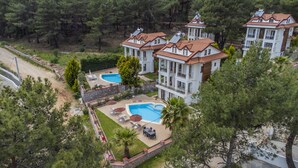 A multi-story building with a pool area, surrounded by trees. - Infinity Olympia Villas (Fethiye)