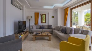 A modern living room with a sofa set, a coffee table, and a television. - Infinity Olympia Villas (Fethiye)