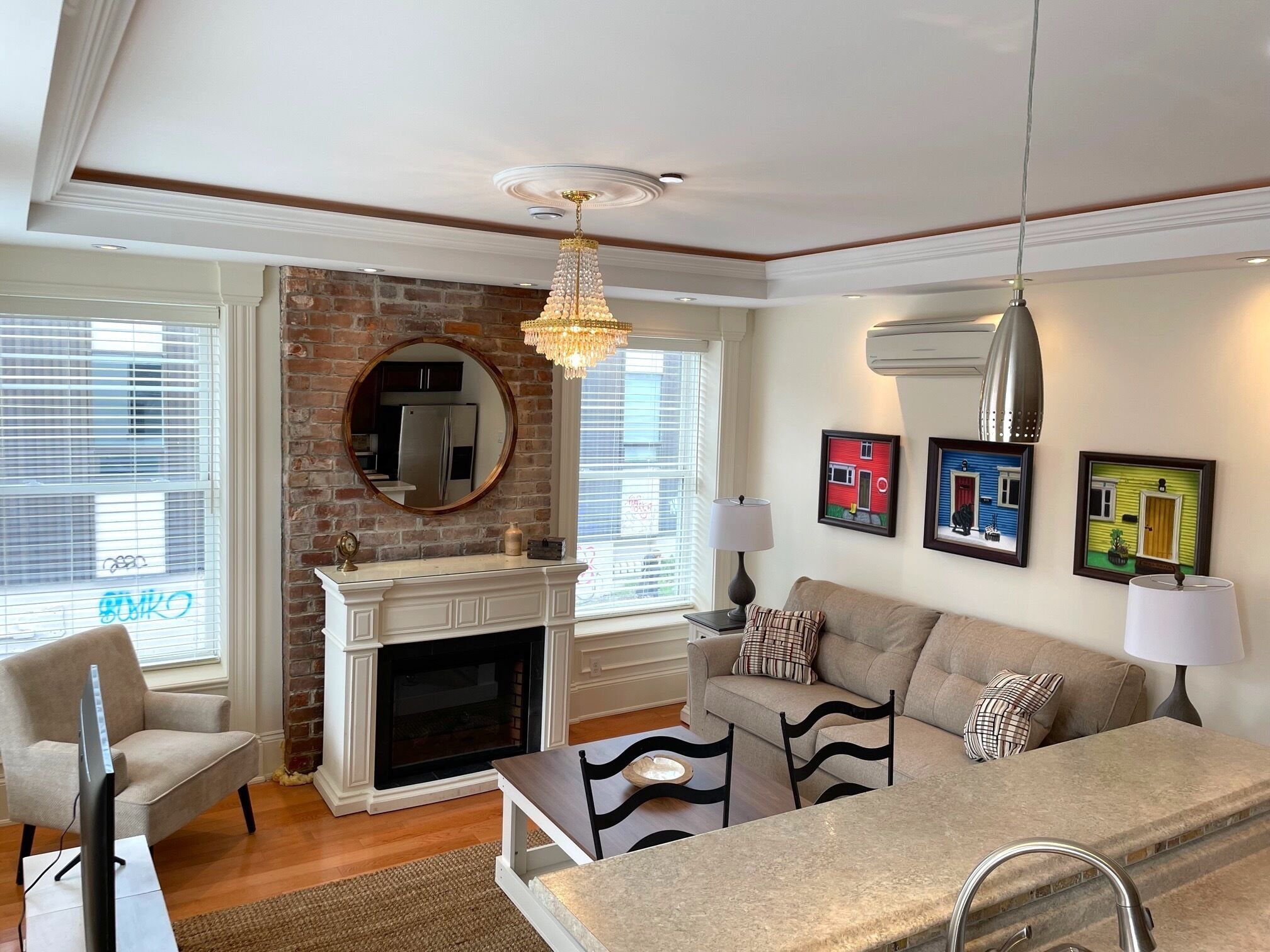 A living room with a fireplace, a sofa set, a dining table, and a chandelier.