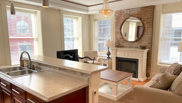 A modern kitchen with a large island, a fireplace, and a cozy seating area.