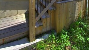 A wooden house with a porch, a staircase, and a wooden fence with the number 110B.