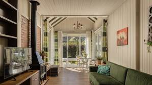 A cozy living room with a green sofa, a TV, and a fireplace. - Pousada Jardim Secreto (Gramado)