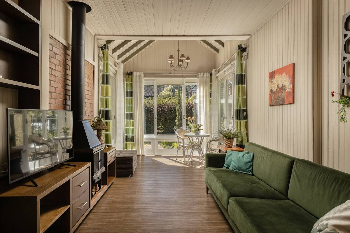 A cozy living room with a green sofa, a TV, and a fireplace.