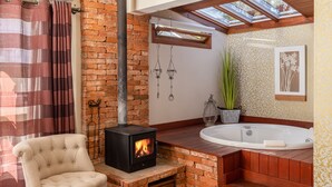 A bathroom with a brick fireplace, a large bathtub, and a window above the sink. - Pousada Jardim Secreto (Gramado)