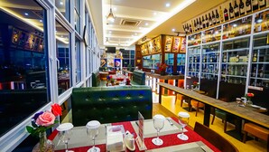 A restaurant with a bar area, seating arrangements, and a view of the cityscape through large windows. - Green Rose Hotel (Batam)