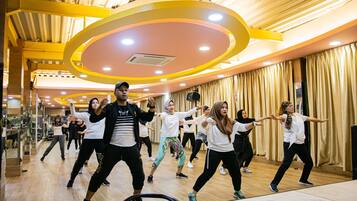Una lezione di danza in una stanza con pavimento in legno e soffitto alto con dettagli gialli.