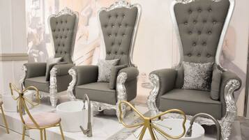 Un'elegante area salotto con poltrone e divano coordinati, caratterizzati da finiture elaborate e un pavimento in marmo.