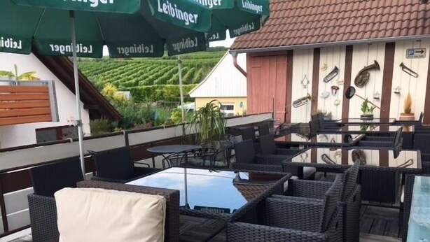 Een terras met rieten meubels en uitzicht op een wijngaard.