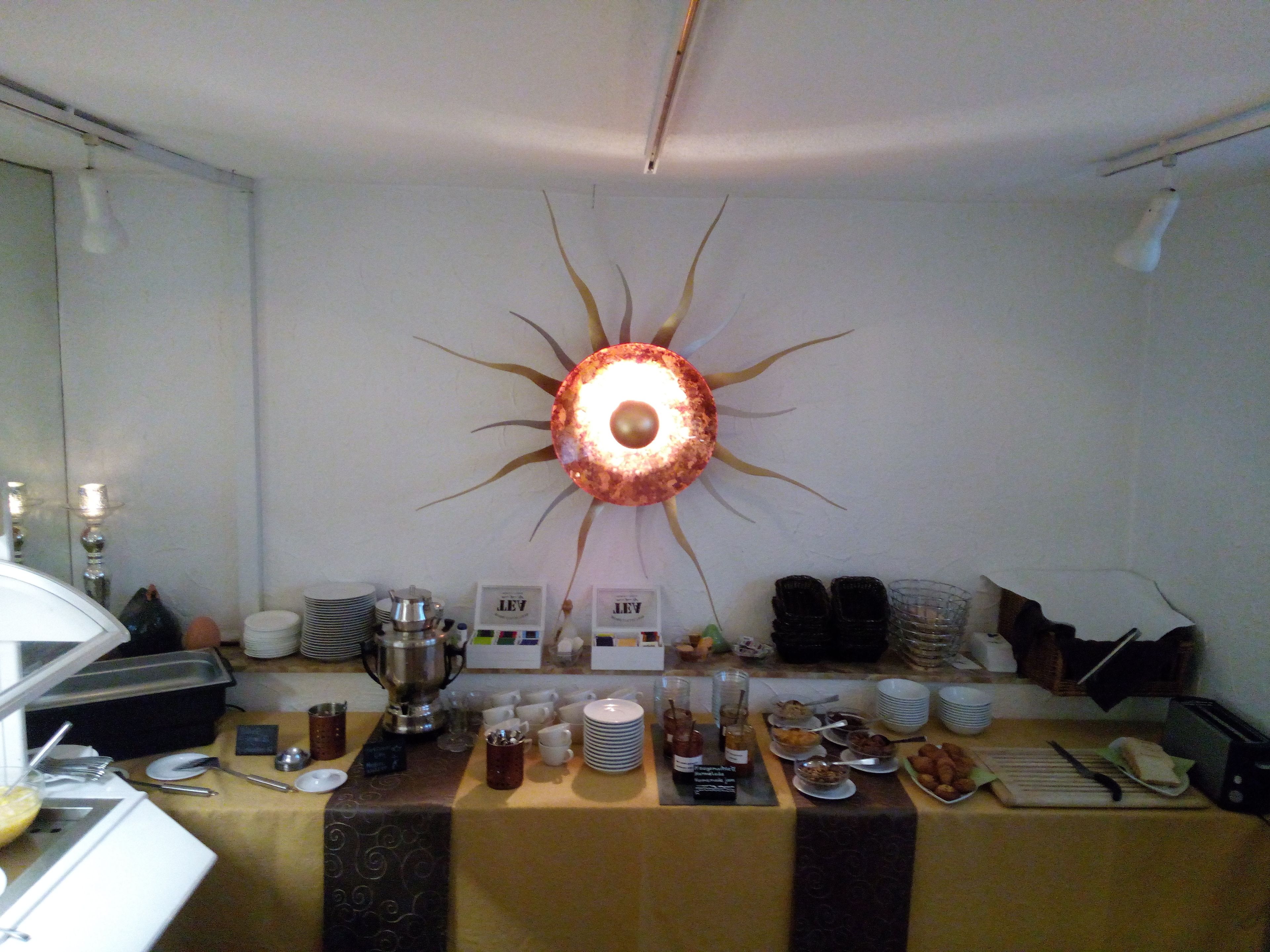 A buffet setup with a decorative wall piece, serving utensils, and various food items.