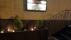 Een receptiegebied met een bord waarop 'Rothaus-Brau' staat, boven een plantenbak met potplanten en kaarsen.