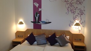 Een hotelkamer met een bed, twee nachtkastjes en een schilderij aan de muur.
