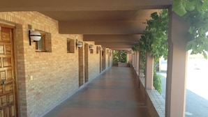 A covered corridor with brick walls, wooden doors, and columns supporting a roof. - Hotel-Motel Sol II (Requena)