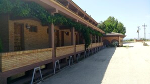 A building with a brick facade, multiple windows, and a covered walkway with vines. - Hotel-Motel Sol II (Requena)