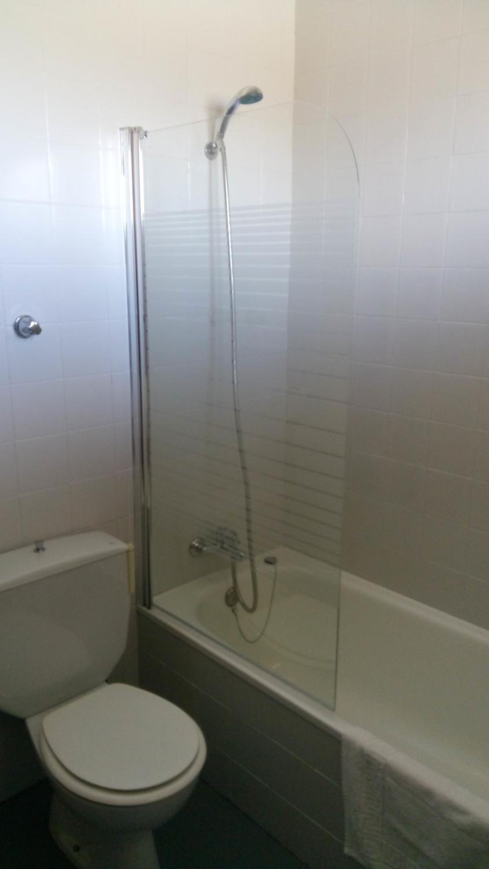 A small bathroom with a toilet, a glass-enclosed shower, and a bathtub.