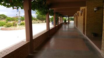 Un paseo techado con paredes de ladrillo y piso de baldosas, que conduce a un edificio con fachada de ladrillo.