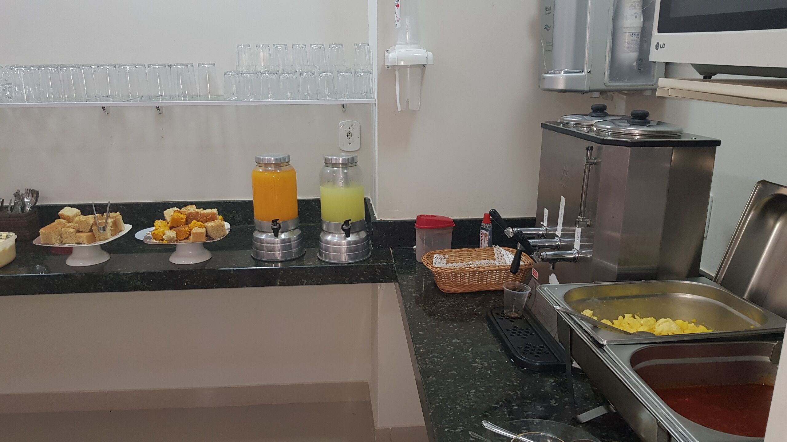 En buffet med forskelligt mad, en juice maskine og et vaskeområde.
