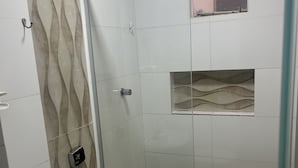 Un bany modern amb dutxa d'estació de vidre, vàter i rentapel.