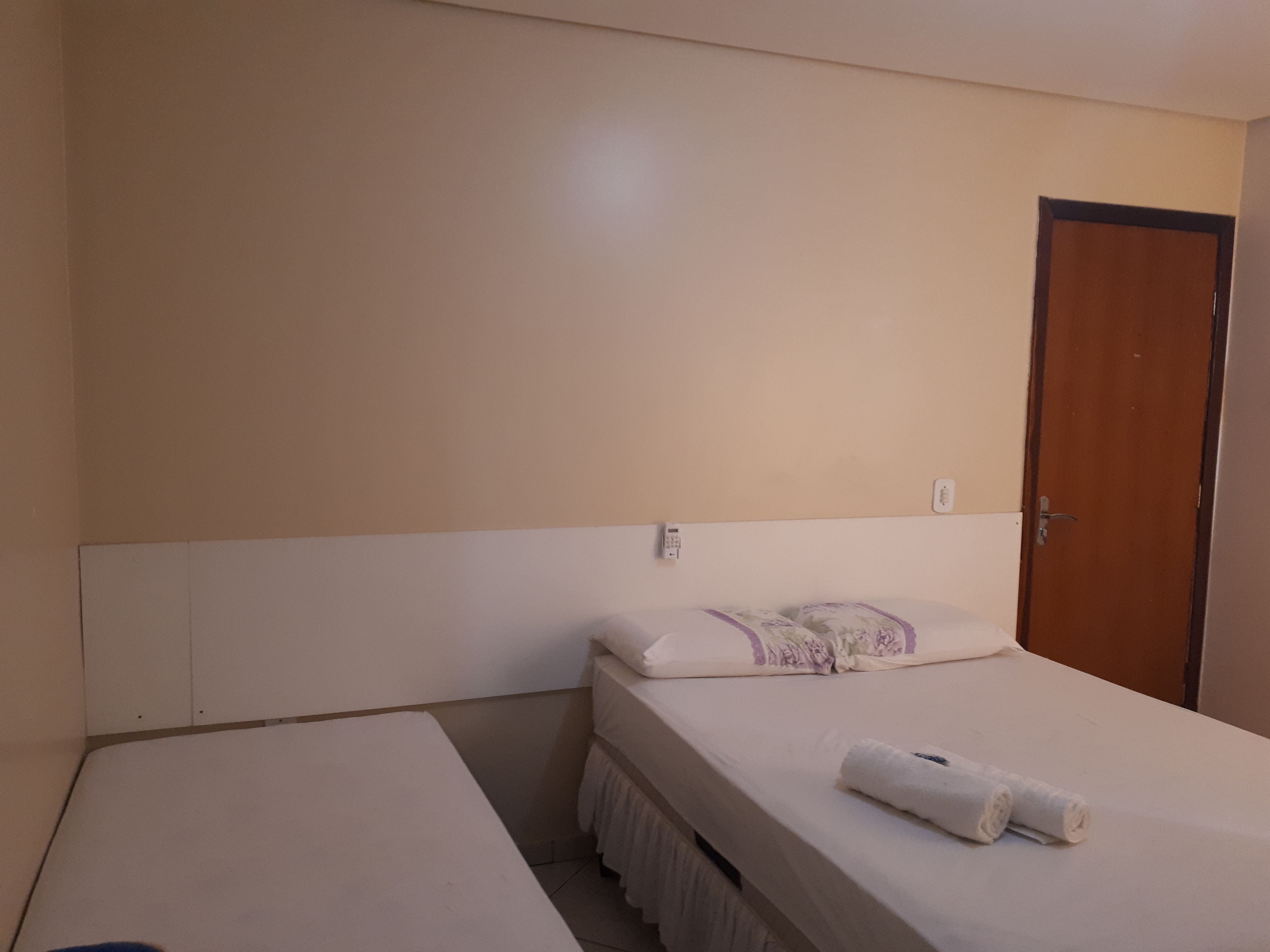 A simple room with a bed, a bedside table, and a door.