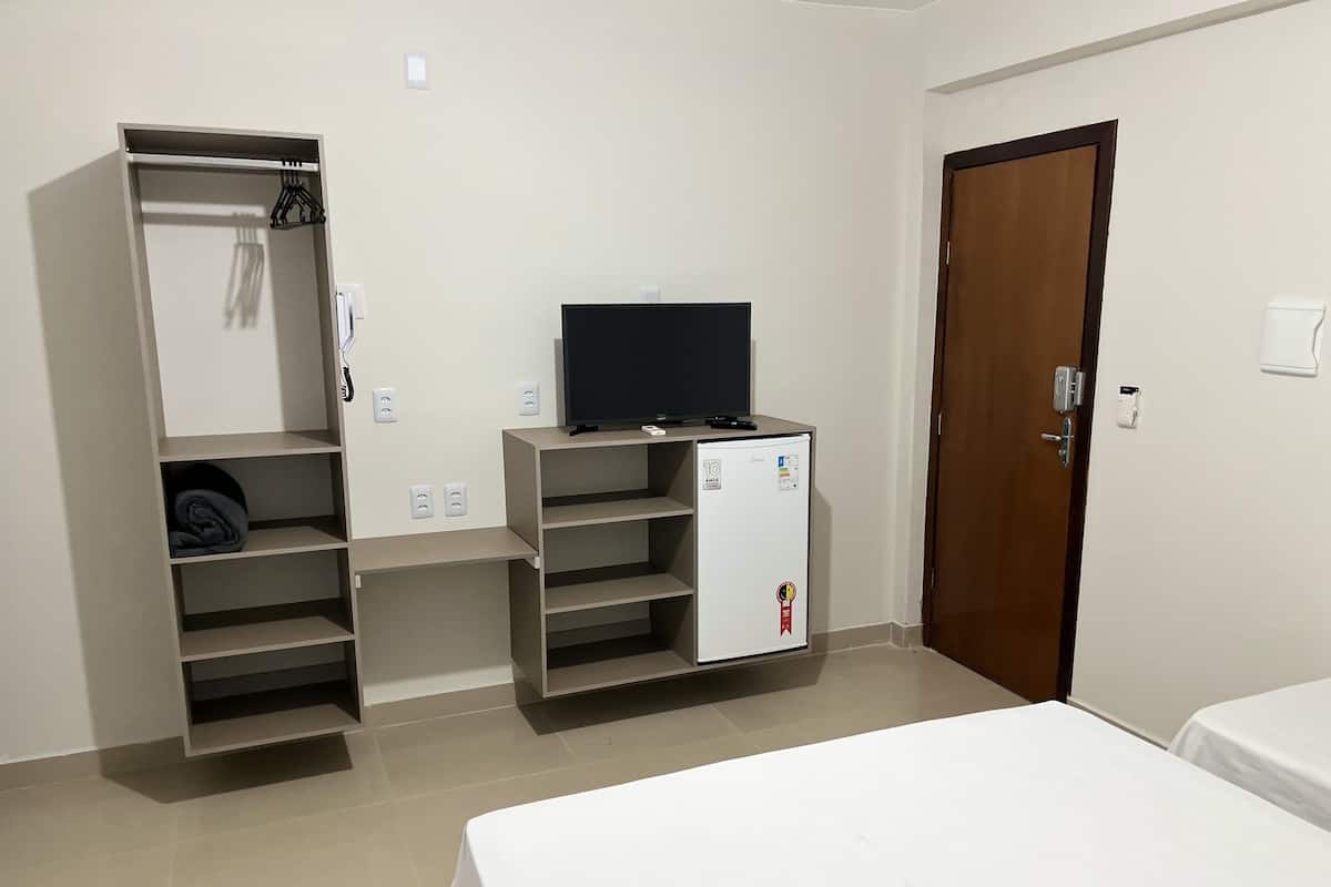A hotel room with a bed, a wardrobe, a television, and a mini-fridge.