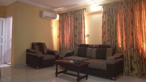 A living room with a sofa, armchair, and coffee table. - New Gate Lodge & Hospitality Ltd (Abuja)