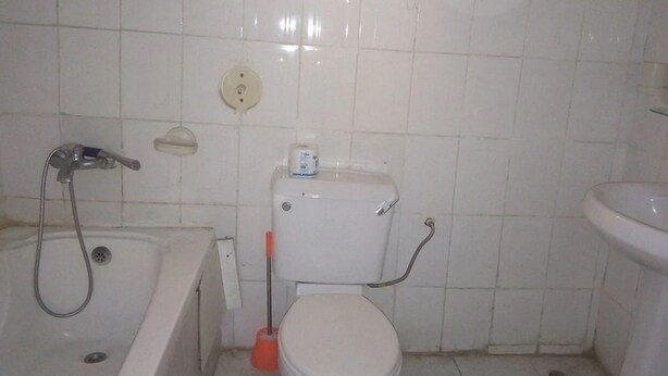 A bathroom with a bathtub, toilet, and a window above the toilet. - New Gate Lodge & Hospitality Ltd (Abuja)