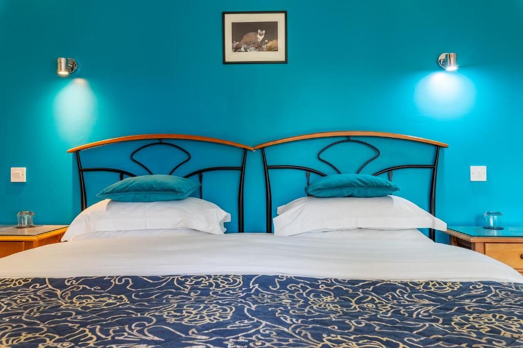 A double bed with a patterned bedspread, two nightstands with lamps, and a framed picture on the wall.
