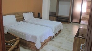 A hotel room with two single beds, a wooden nightstand, a small table, and a wardrobe. - Auberge le Rajah (Quatre Bornes)