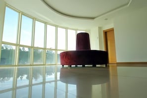 A spacious room with large windows, a polished floor, and a red cylindrical object. - Green Suada Hotel (Pazar)