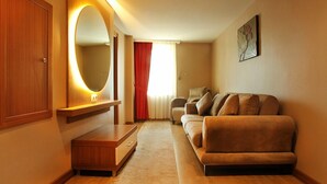 Une chambre d’hôtel avec une armoire en bois, un canapé, un miroir et un tableau au mur.