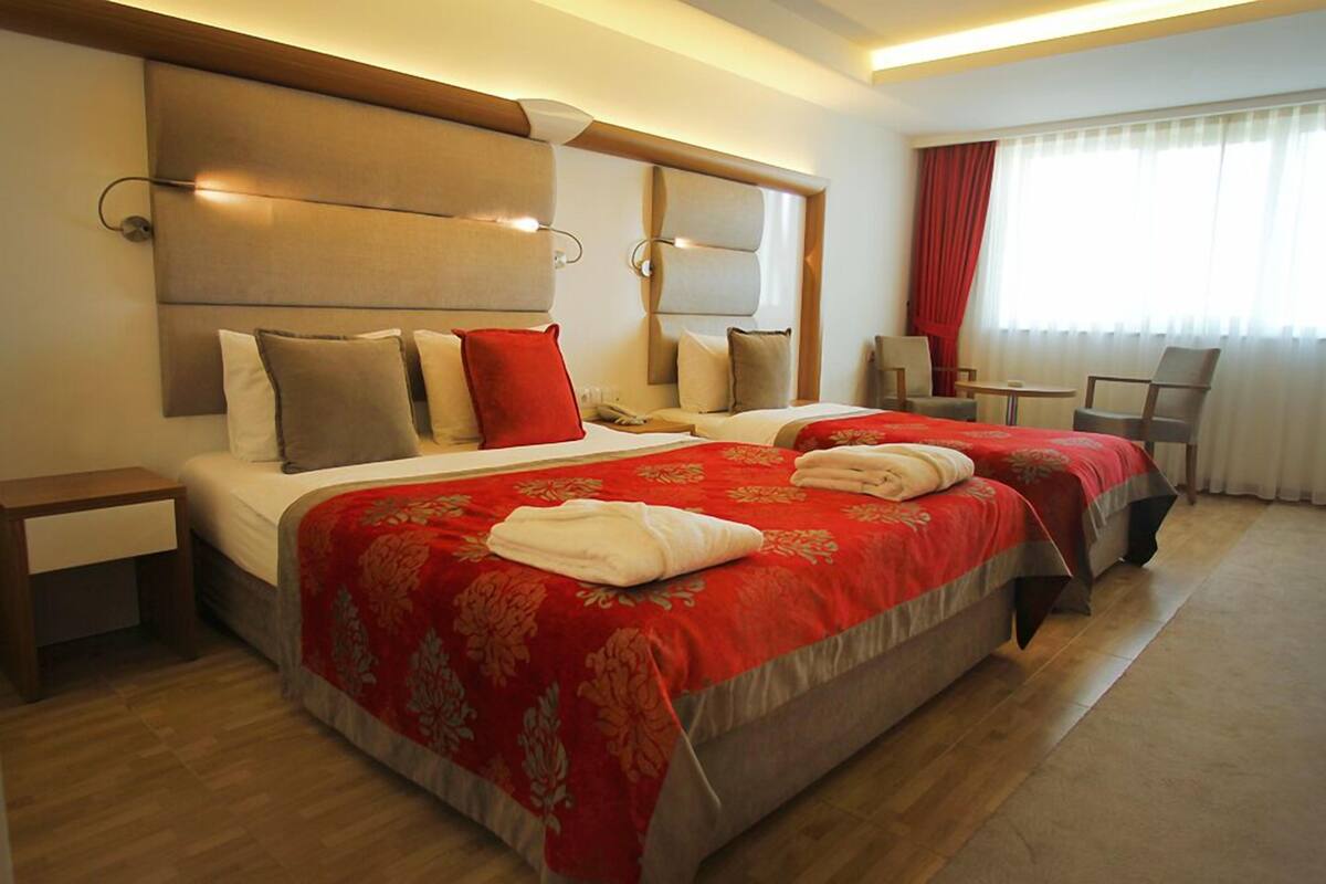 A hotel room with two beds, a nightstand, a chair, and a desk.