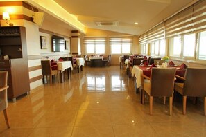 A spacious restaurant with a long counter, multiple tables, and chairs. - Green Suada Hotel (Pazar)