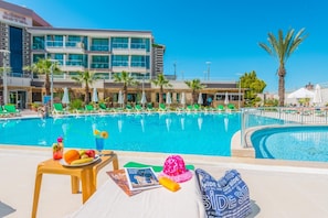 Una piscina al aire libre, sombrillas, tumbonas