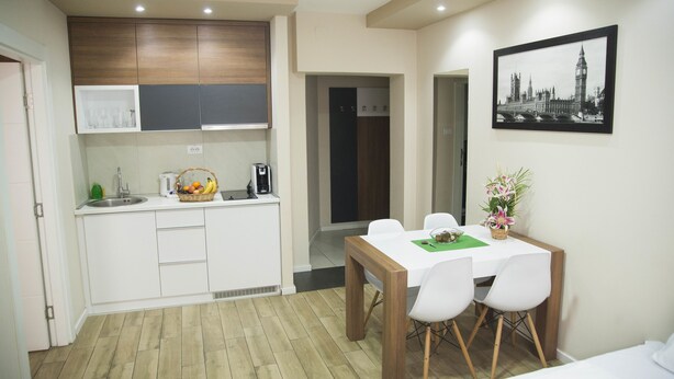 Habitación de hotel compacta con kitchenette, comedor con mesa y sillas, y cama.