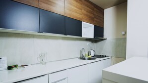 Una cocina moderna con armarios blancos, un lavamanos de acero inoxidable y un hervidor.