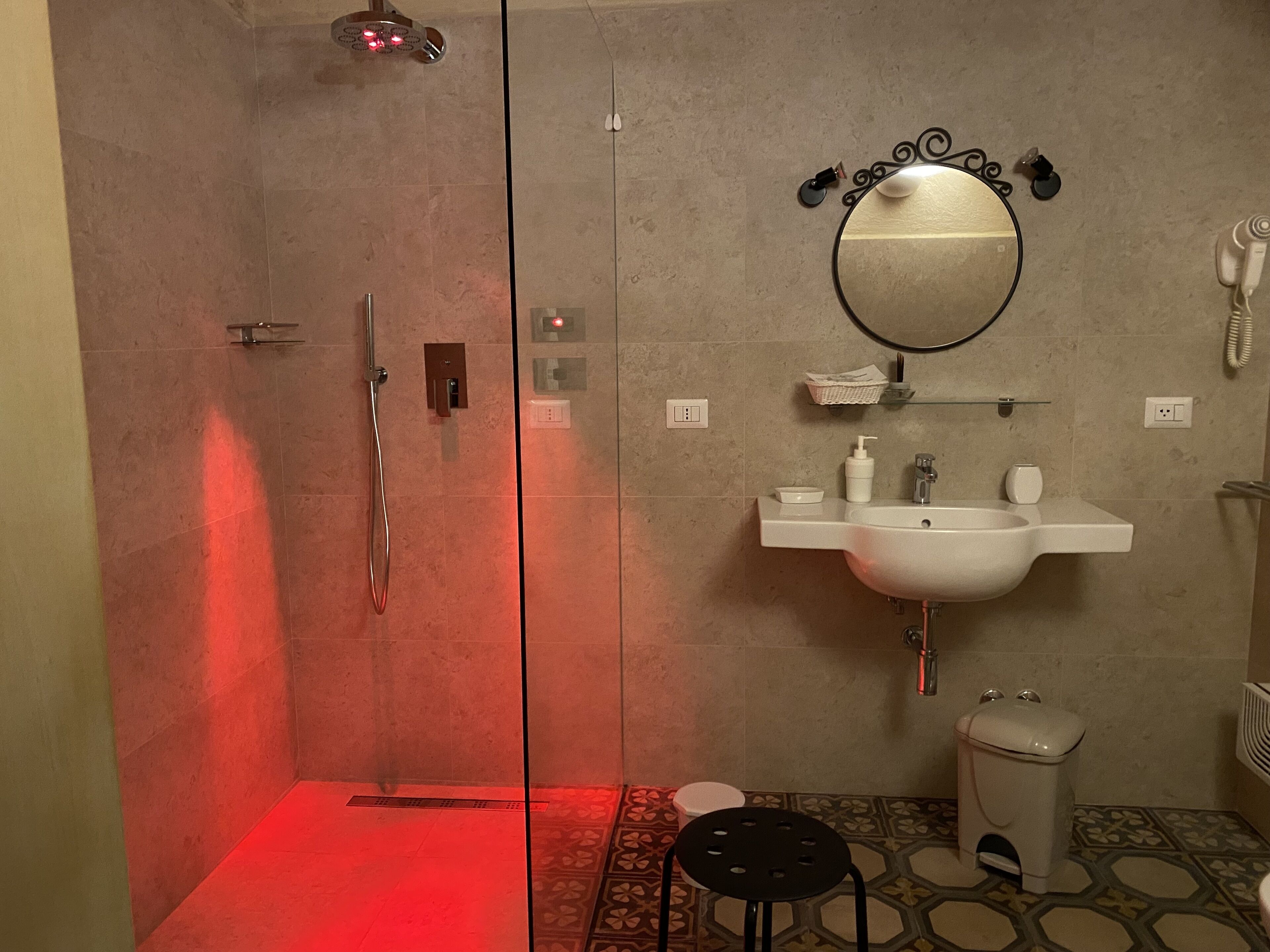 A modern bathroom with a glass-enclosed shower, a sink with a mirror above it, and a toilet.