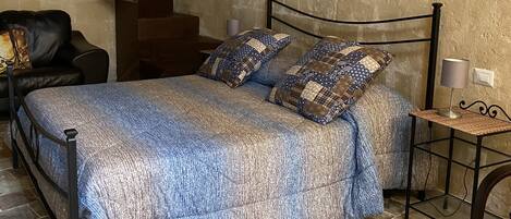 Un dormitorio con cama, una silla, una lámpara y una escalera.