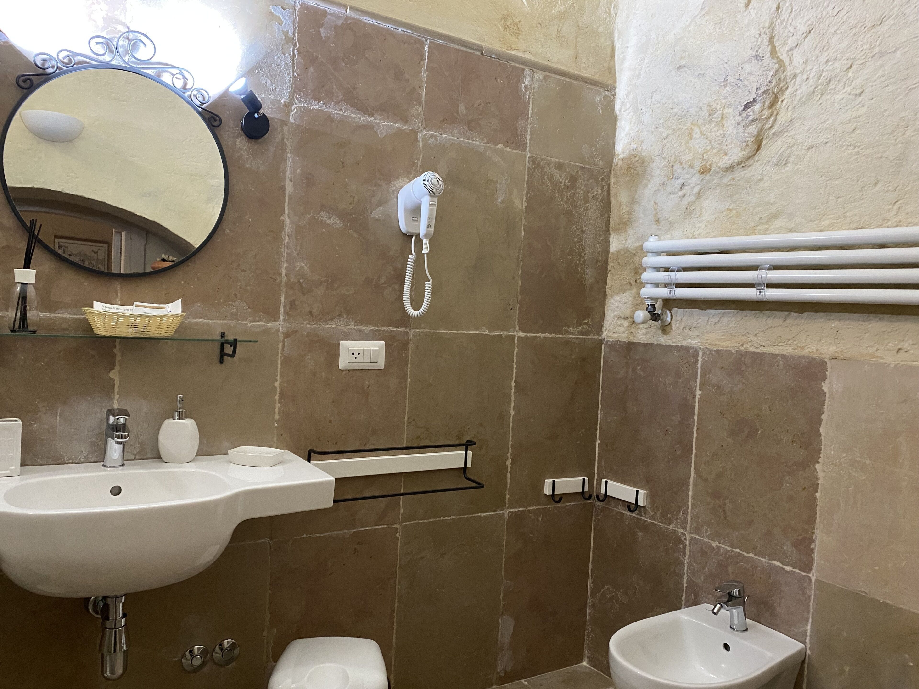 Une salle de bain équipée d’un lavabo, d’un miroir, de toilettes, d’un bidet et d’un porte-serviettes.