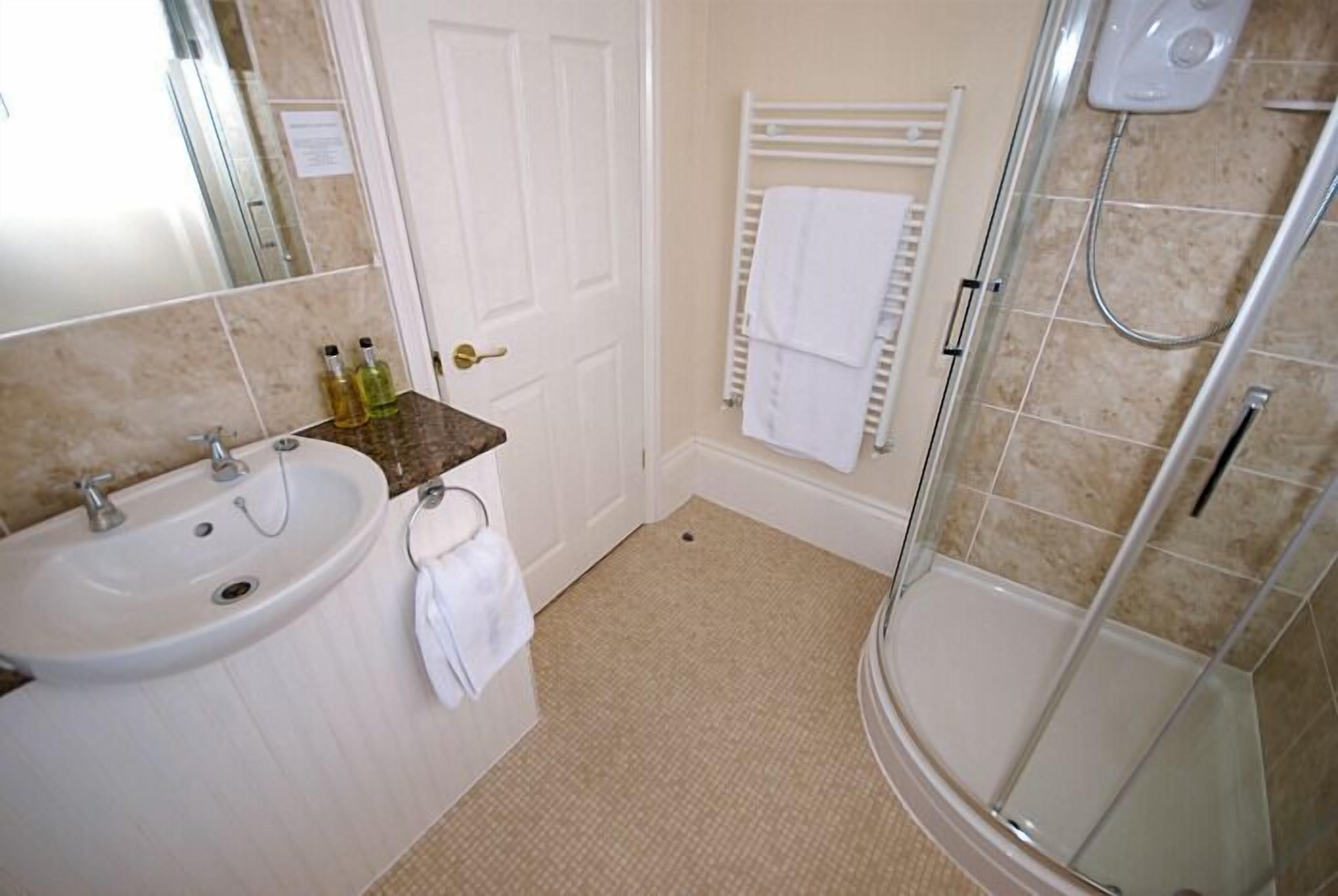 A bathroom with a sink, mirror, towel rack, and shower.