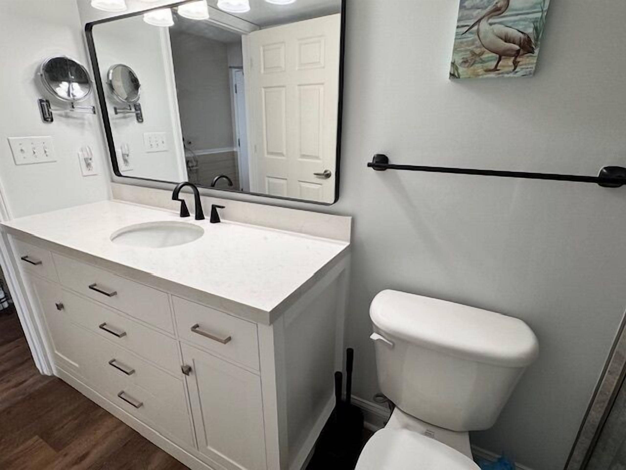 A bathroom with a white sink, mirror, and toilet.