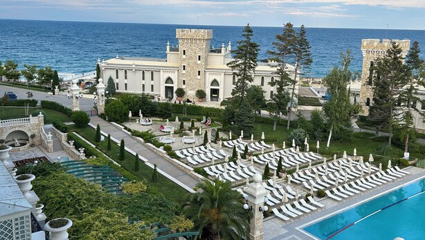 A resort with a pool, lounge chairs, and a view of the sea. - Astor Garden Hotel (Varna)