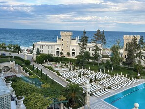 A resort with a pool, lounge chairs, and a view of the sea. - Astor Garden Hotel (Varna)
