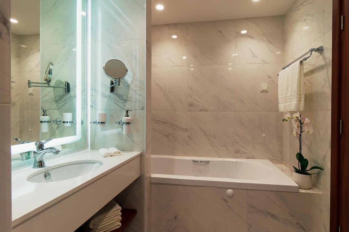 Un baño moderno con dos lavamanos, una bañera y un espejo grande.