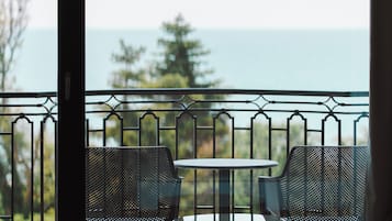 A balcony with two chairs and a small table, overlooking a body of water and trees.