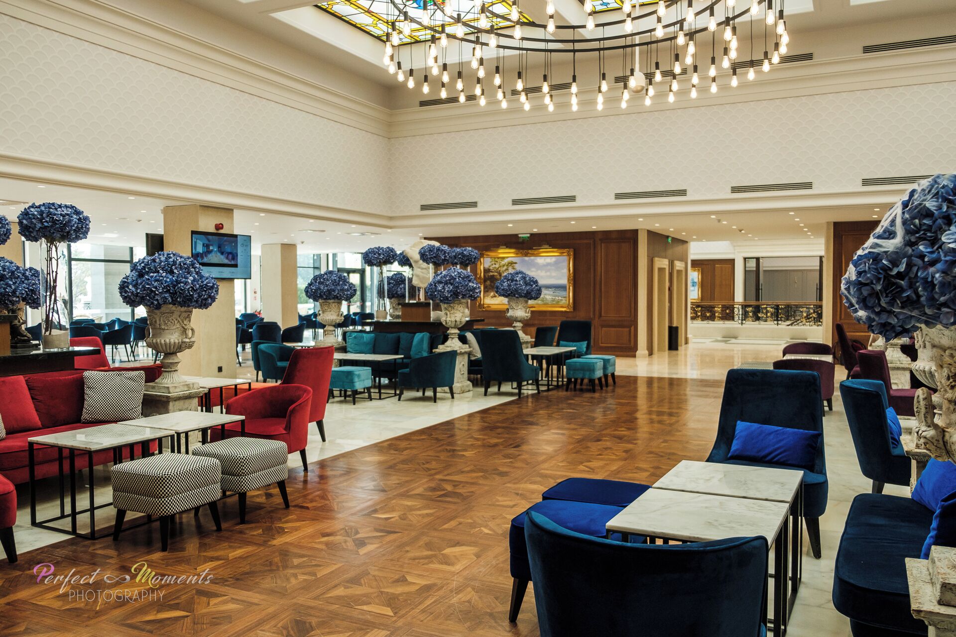 Un vestíbulo espacioso con muebles modernos, un gran candelabro y flores azules decorativas.