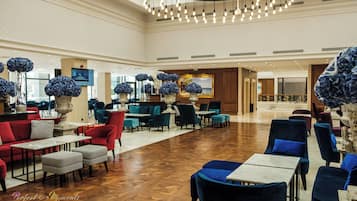 Un vestíbulo espacioso con muebles modernos, un gran candelabro y flores azules decorativas.
