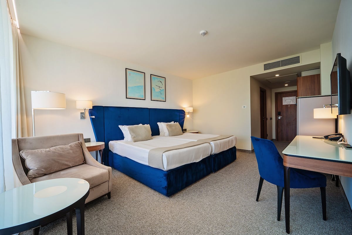 A hotel room with a large bed, two bedside tables, a desk, a chair, and a TV.